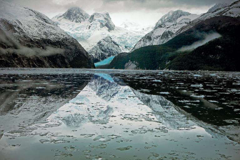 A splash of azure, of the kind Darwin noted, is reflected in a bay in Tierra del Fuego, Chile. The Darwin mountain range, named for the young naturalist by Captain FitzRoy in 1834, rises above it
